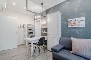 A compact living space with a dining table, a sofa, and a kitchenette. - GuestHost - Cozy Central Flat near Porta Nuova (Turin)