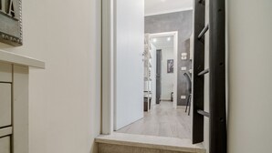 A hallway with a staircase leading to another room, a white door, and a light switch on the wall. - GuestHost - Cozy Central Flat near Porta Nuova (Turin)