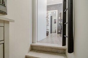 A hallway with a staircase leading to another room, a white door, and a light switch on the wall. - GuestHost - Cozy Central Flat near Porta Nuova (Turin)