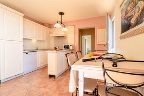 Una cocina con armarios blancos, un microondas y un comedor con mesa y sillas.