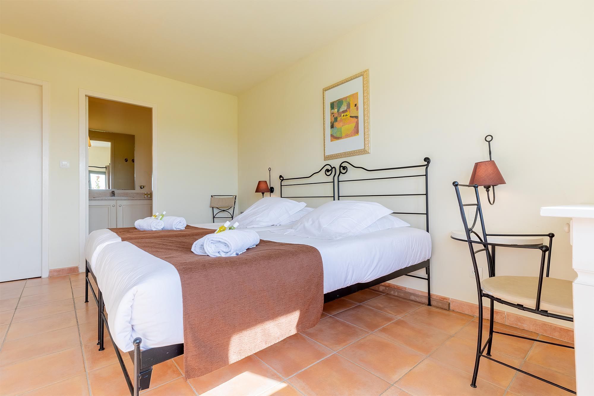 Ein Hotelzimmer mit einem Bett, einem Sessel, einem Tisch, einem Spiegel und einem Bild an der Wand.