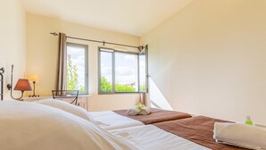 Ein Hotelzimmer mit zwei Betten, einem Fenster mit Vorhängen, einer Nachttischlampe und einem Handtuch auf dem Boden.