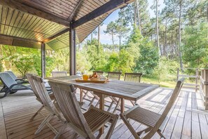 Eine Holzterrasse mit Tisch und Stühlen, umgeben von Bäumen.
