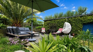 A patio with a sofa, chairs, a hanging chair, and a table. - Holiday Home “Le Petit Baigneur” with Private Terrace, Shared Garden & Wi-Fi (Plouha)