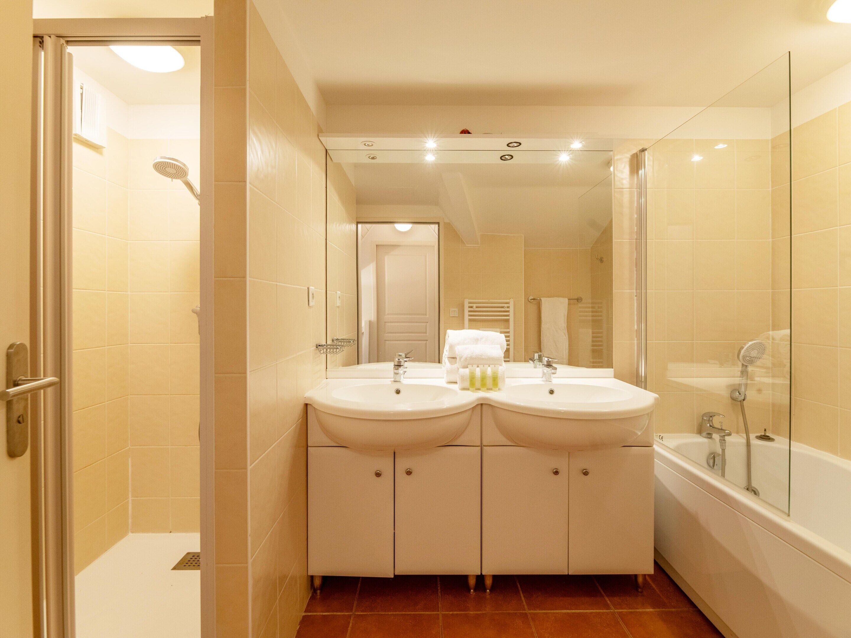 A bathroom with two sinks, a shower, and a glass-enclosed bathtub.