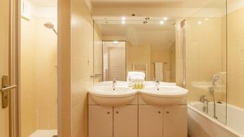 A bathroom with two sinks, a shower, and a glass-enclosed bathtub.