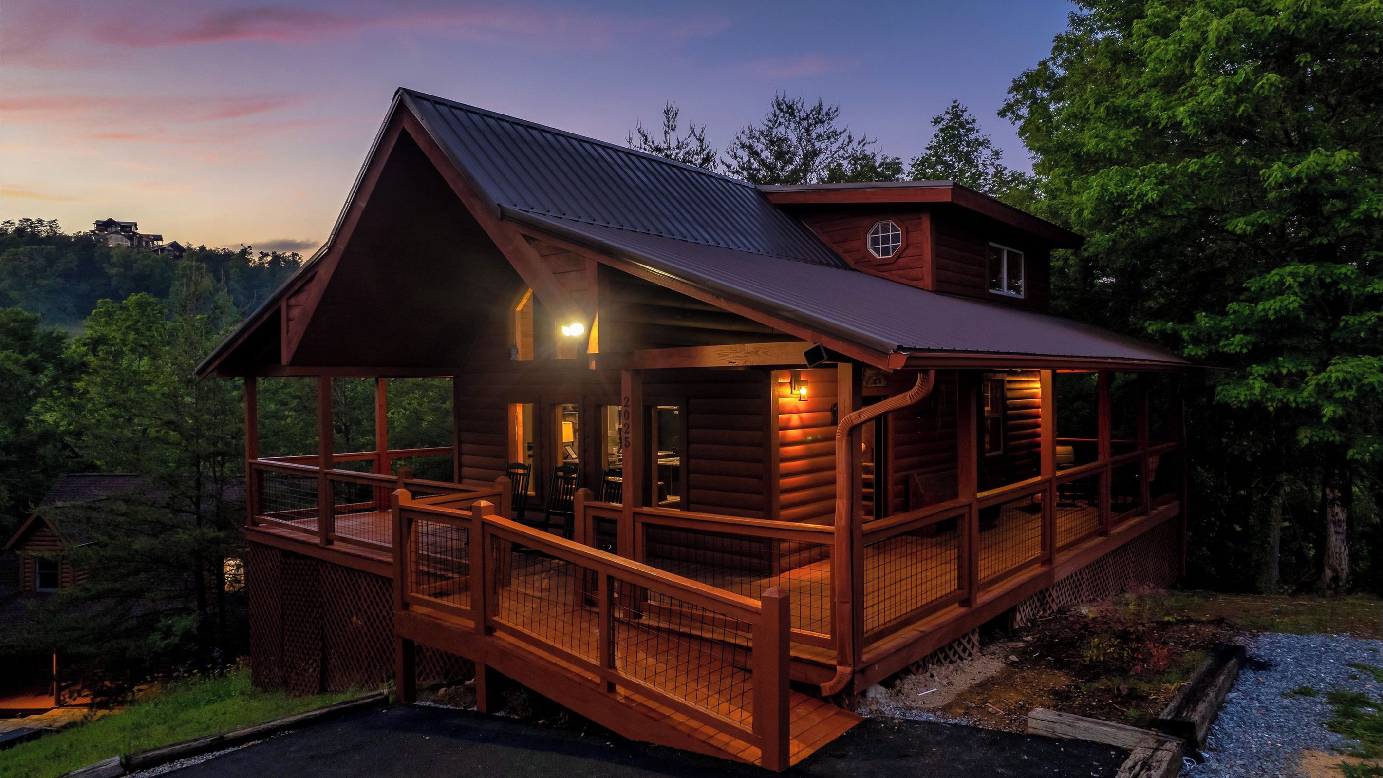 A log cabin with a balcony, a covered porch, and a metal roof.