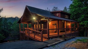 A log cabin with a porch, a staircase, and a deck.