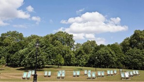 A grassy area with rows of lounge chairs and a lamp post. - Charming Studio Apartment near 3 Museums (London)