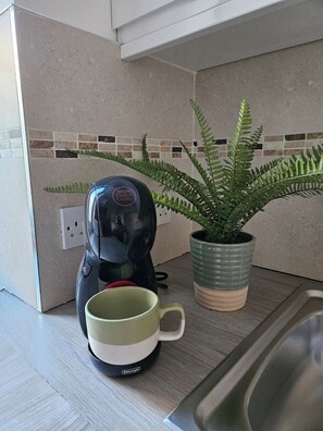 A kitchen with a coffee maker, a mug, and a potted plant. - Charming Studio Apartment near 3 Museums (London)