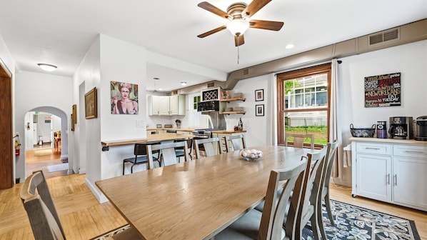 A modern kitchen with a dining area, wooden cabinets, a ceiling fan, and a view of the outdoors.