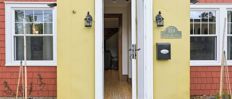 A yellow building with a white door, two windows, and a mailbox.