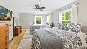 A bedroom with two beds, a ceiling fan, a dresser, a desk, and a large window with curtains. - Walk to Downtown Sturgeon Bay! Large Home + Yard (Sturgeon Bay)