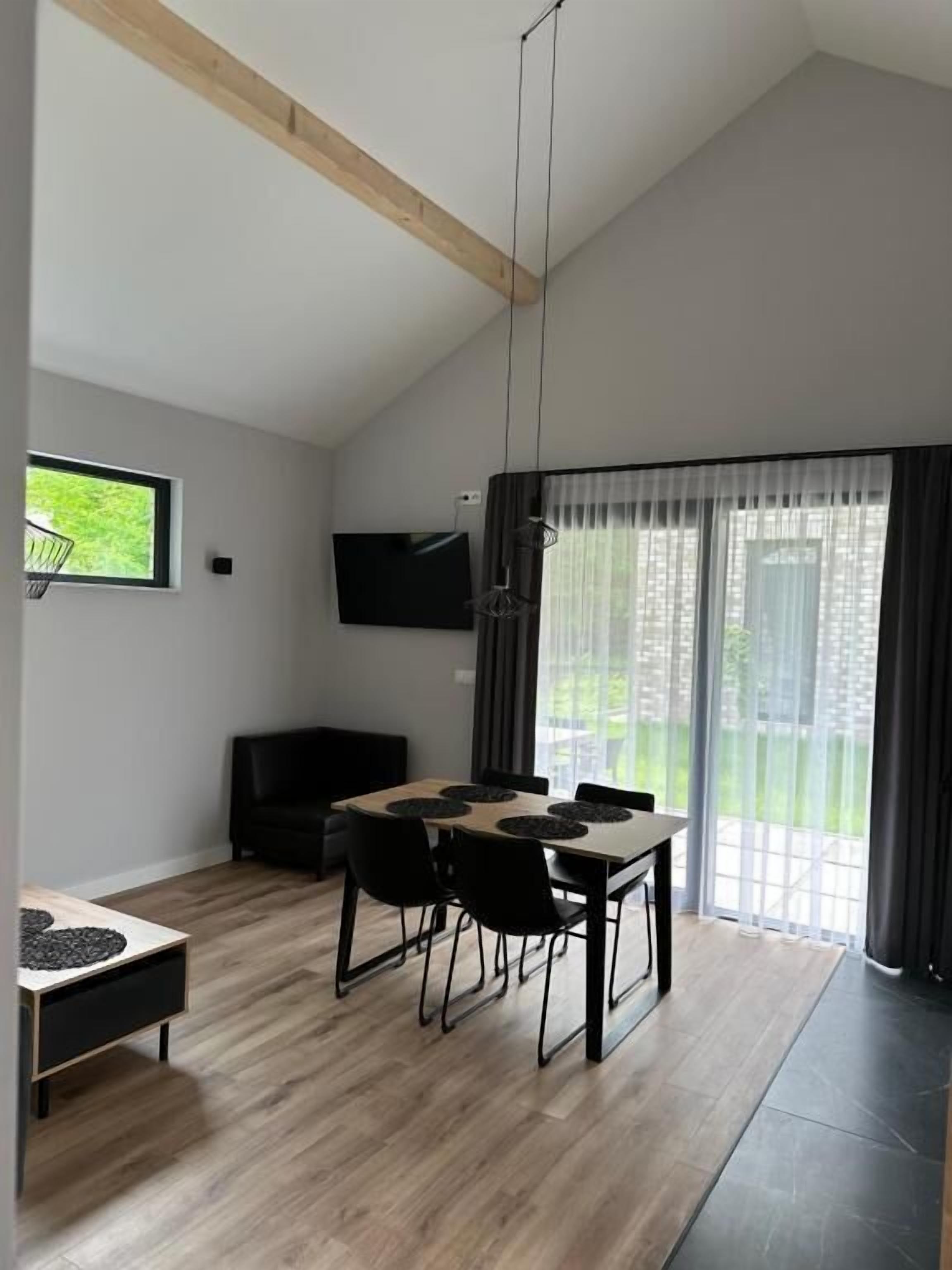 A modern living room with a dining area, a flat-screen TV, and a large sliding glass door to a balcony.