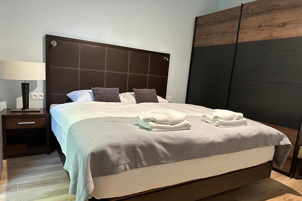 Une chambre d’hôtel avec un grand lit, une table de chevet avec une lampe et une armoire.