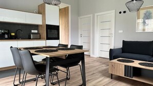 A modern kitchen with a dining table, chairs, and pendant lights. - Domki Zdrojowe  (Polanica-Zdrój)