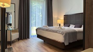 A modern hotel room with a large bed, a bedside table, a mirror, and a window with curtains. - Domki Zdrojowe  (Polanica-Zdrój)