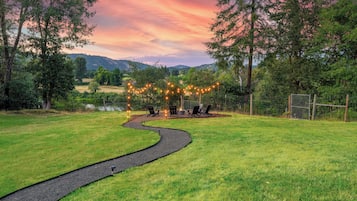 Un giardino curato con un vialetto sinuoso, posti a sedere all'aperto e luci decorative.