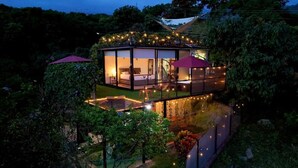 A modern glass house with a balcony, surrounded by lush greenery. - Oasis Glamping Tena Cundinamarca (Tena)