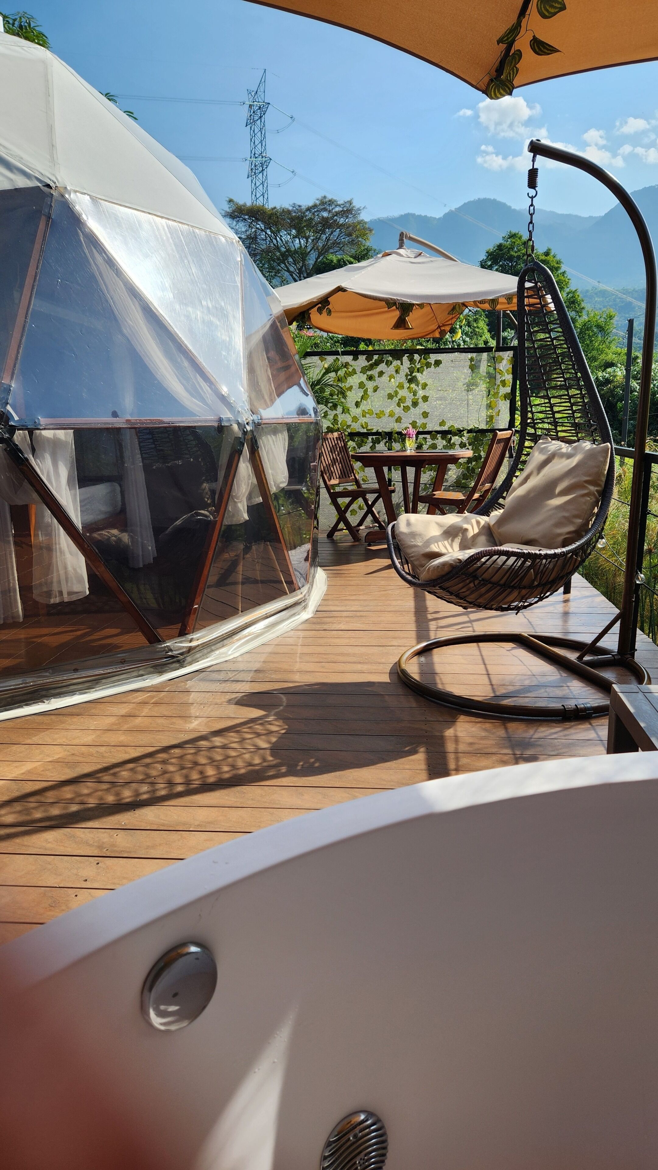 Una terraza de madera con una hamaca colgante y una estructura de carpa transparente.