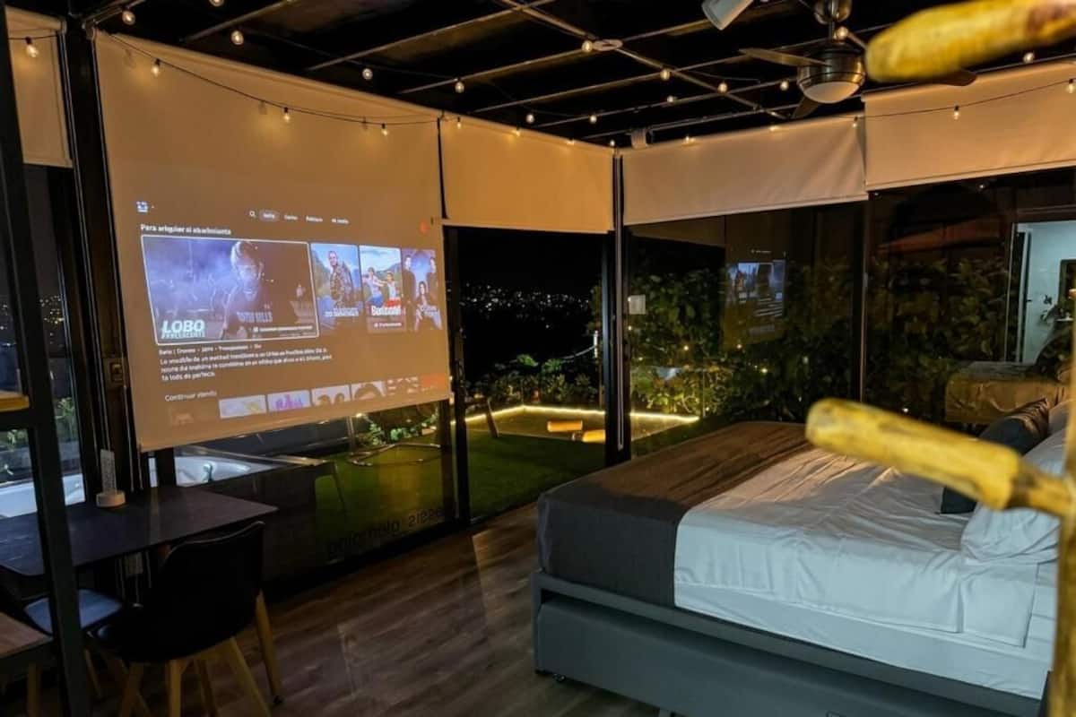 Habitación de hotel moderna con una cama grande, un escritorio y un balcón con vistas a la ciudad.