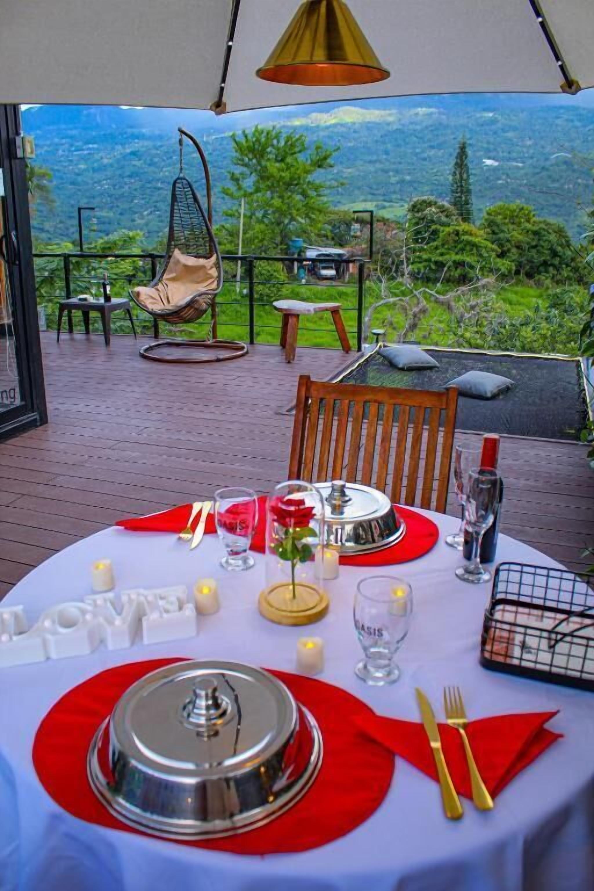 A dining table set for two with a view of a mountainous landscape.