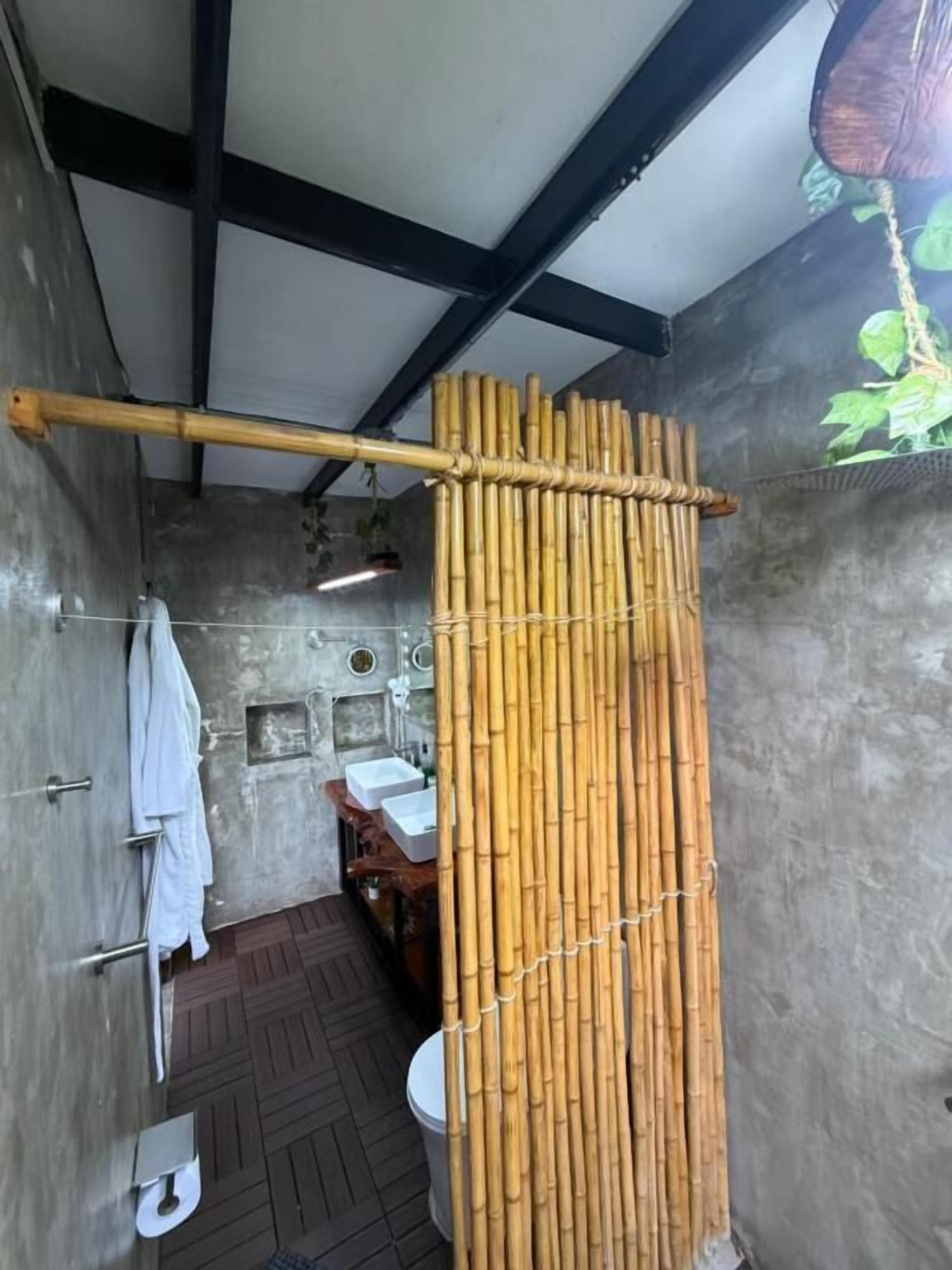 Un baño con cortina de bambú, inodoro, lavabo y toallero.