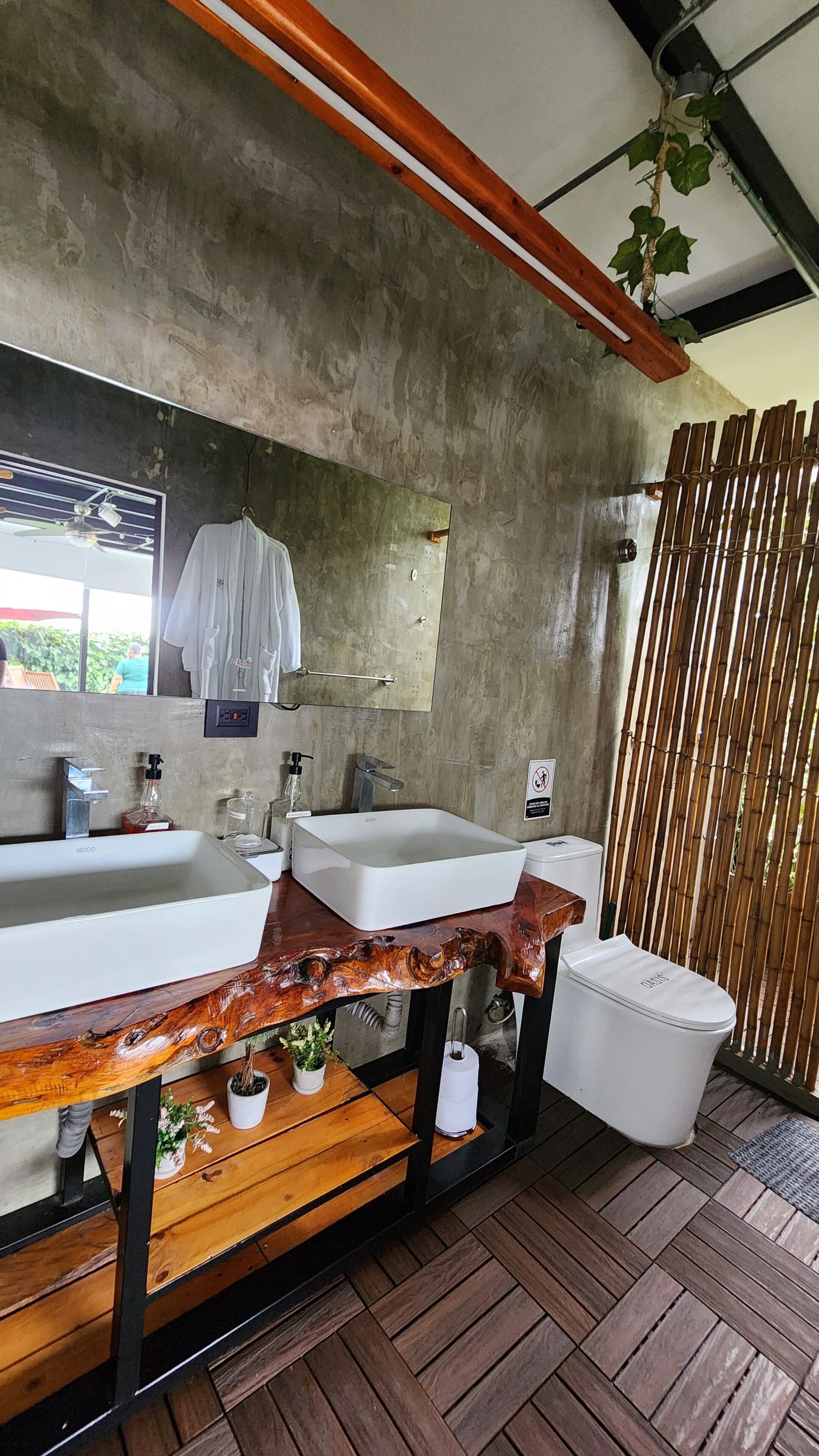 Un baño con dos lavamanos, un espejo, un mueble de tocador de madera y un separador de bambú.