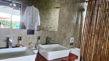 Un baño con dos lavamanos, un espejo, un mueble de tocador de madera y un separador de bambú.