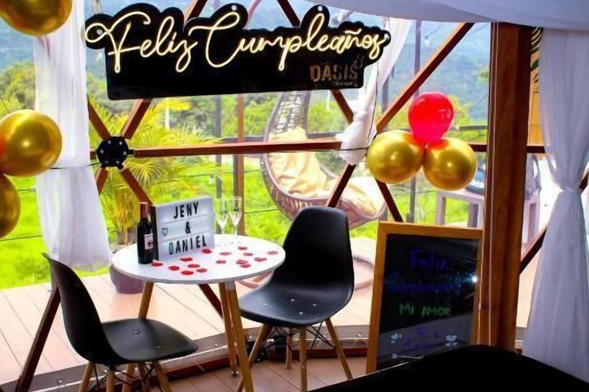 Un área al aire libre con toldo, una mesa, sillas y un letrero que dice 'Feliz Cumpleaños'.