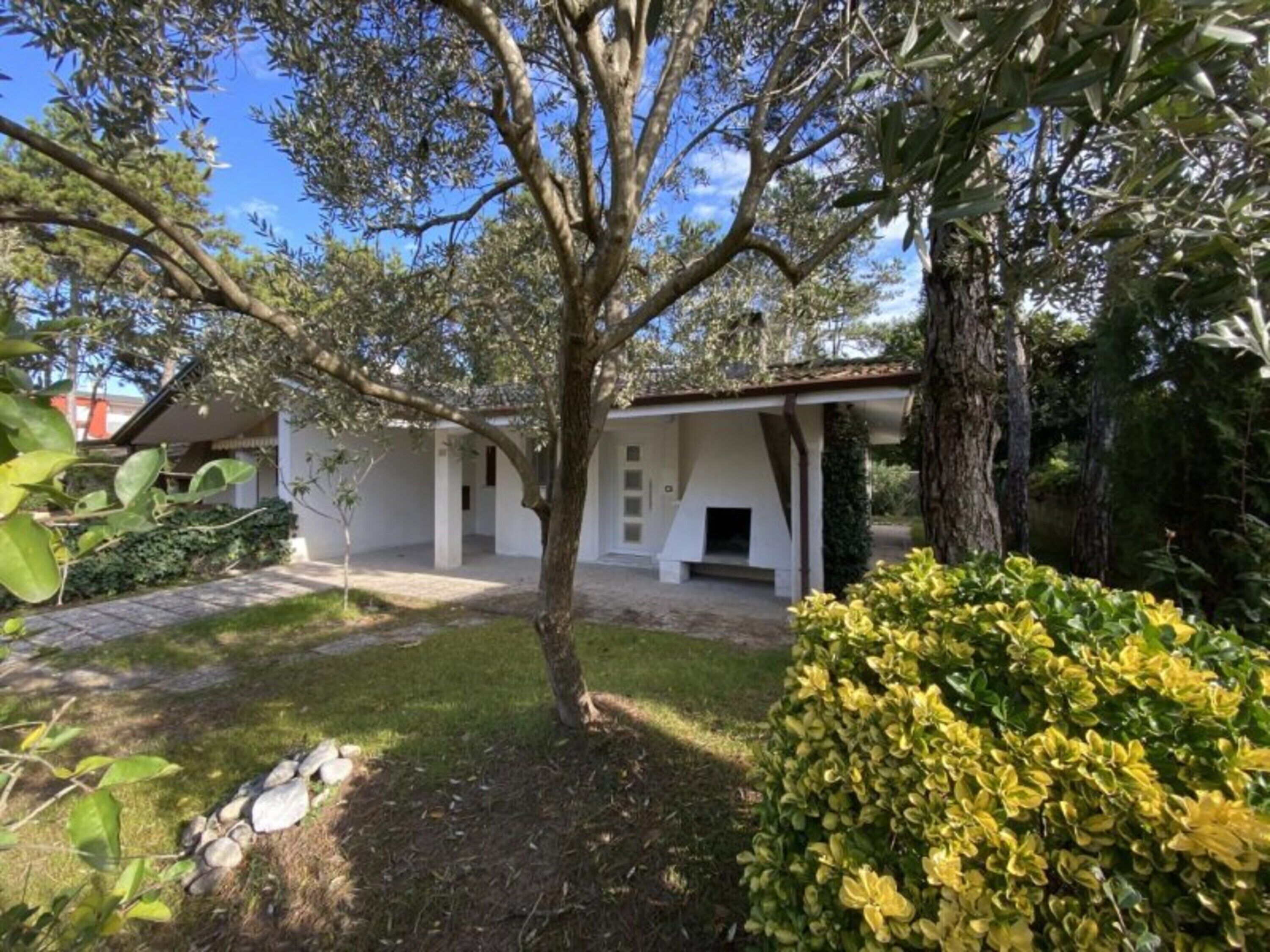 Un bâtiment blanc doté d’un patio abrité, entouré d’arbres et d’une pelouse bien entretenue.
