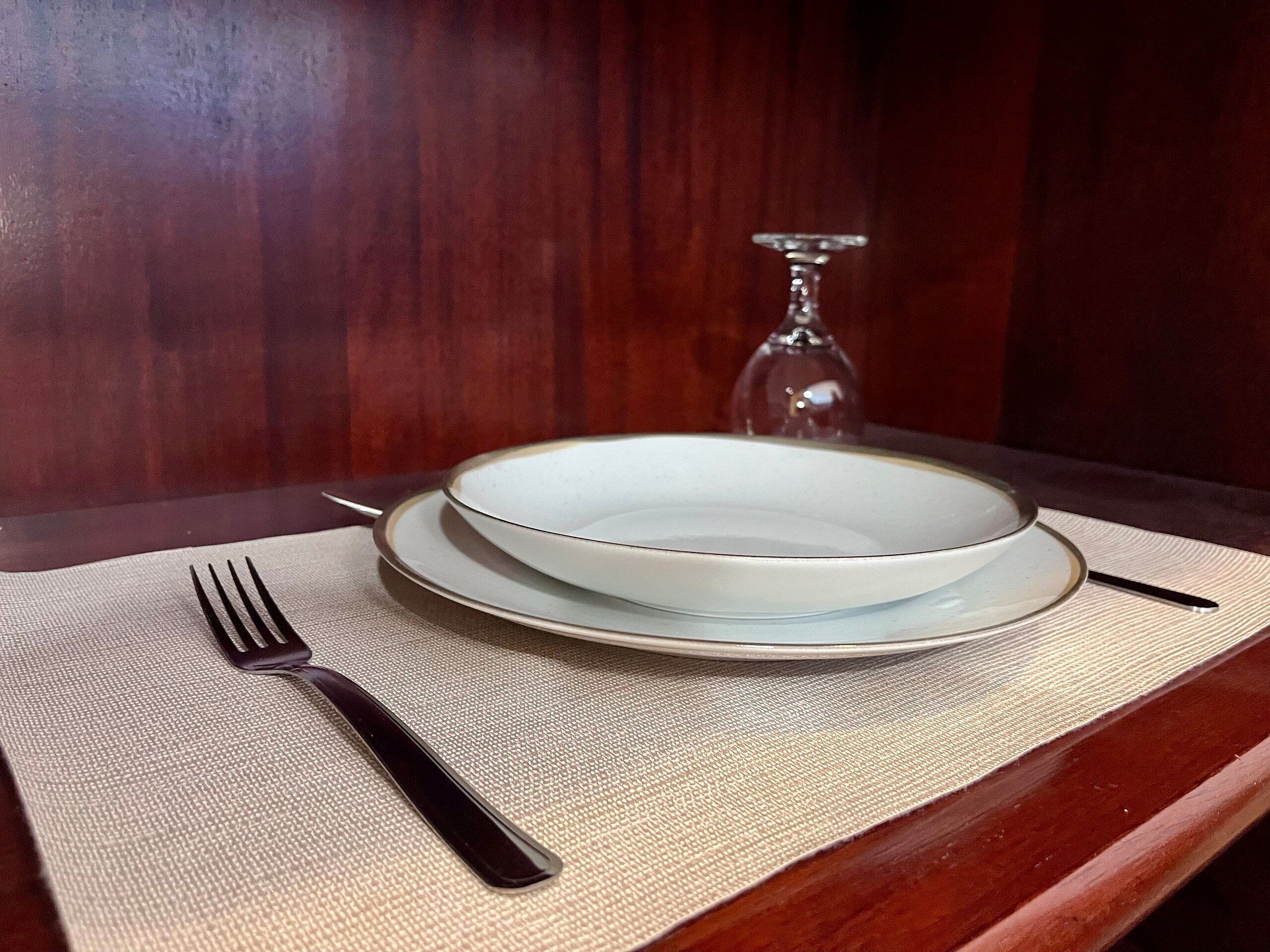 Uma mesa de jantar com um prato, um copo e talheres.