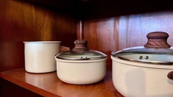 Three white ceramic containers with lids on a wooden shelf.