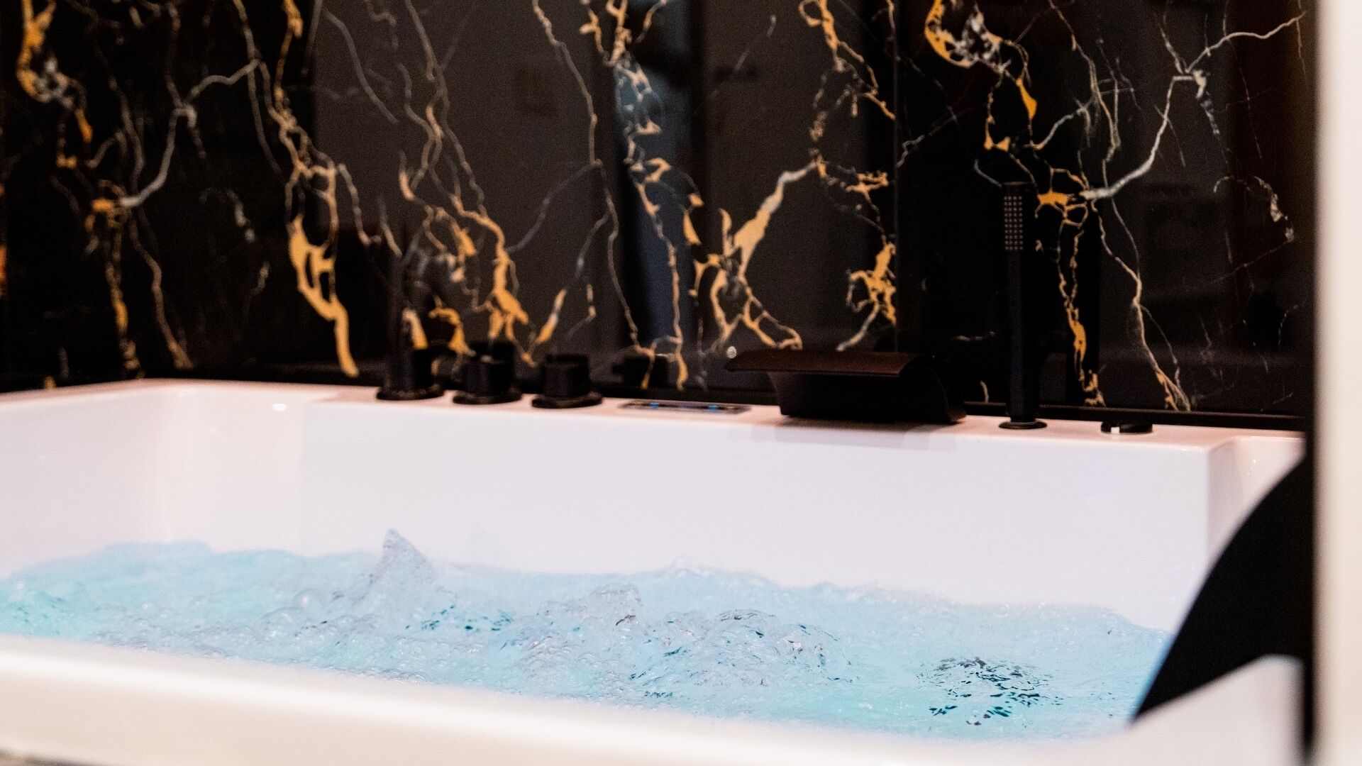 A bathtub with a marble-like wall and a water feature.