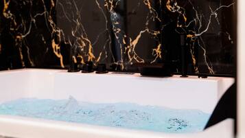 A bathtub with a marble-like wall and a water feature.