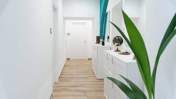 A hallway with a wooden floor, white walls, and a door at the end.