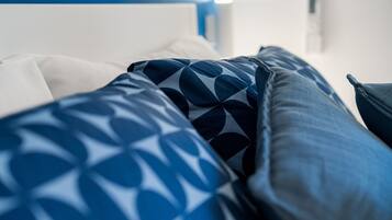 Una cama con almohadas estampadas y un cabecero blanco.
