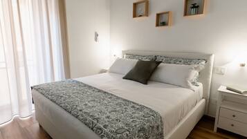 Un dormitorio ordenado con cama, mesitas de noche y ventana con cortinas.