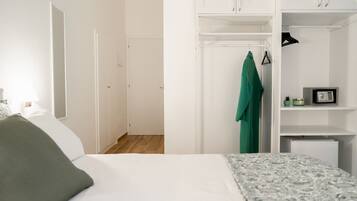 Un dormitorio con cama, armario y perchero.