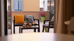 A balcony with a sofa, two chairs, a small table with drinks, and potted plants. - Harmonia Rooms (Civitavecchia)