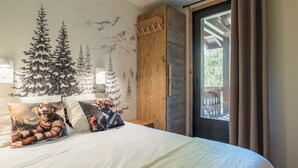 Une chambre à coucher avec un lit, des oreillers, une armoire en bois, une fenêtre avec des rideaux et une fresque murale.