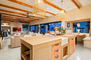 Una cocina amplia con una isla grande, vigas de techo de madera e iluminación colgante.