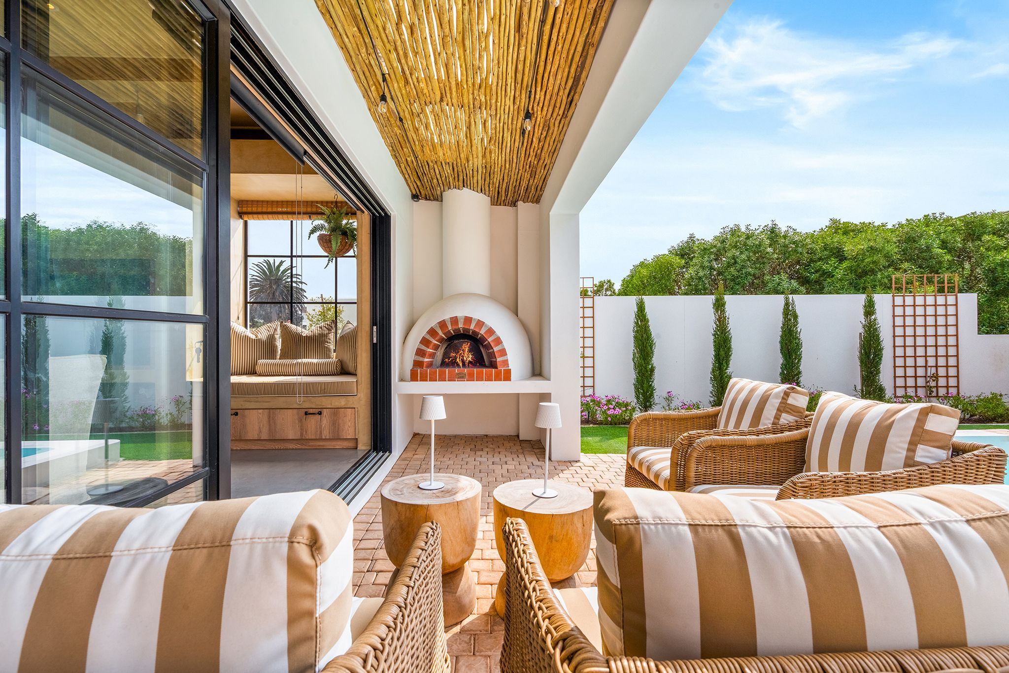 Un espace extérieur aménagé avec des meubles en osier, une cheminée et une vue sur le jardin.