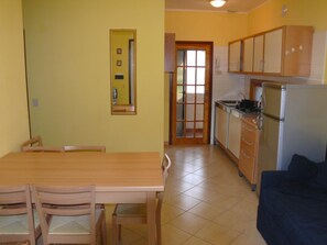 Eine kleine Küche mit Essbereich, einem Kühlschrank und einer Couch.