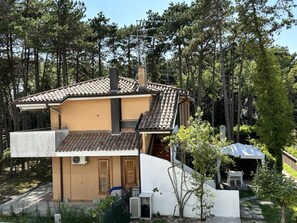 Ein zweigeschossiges Haus mit Ziegeldach, Schornstein und einer kleinen Veranda mit Gartenmöbeln.