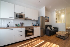 Eine moderne Küche mit weißen Schränken, einer eingebauten Mikrowelle, einem Edelstahlkühlschrank und einer Holz Arbeitsplatte.