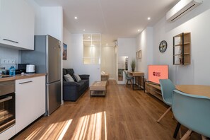 Eine moderne Küche mit Kühlschrank, Mikrowelle und Backofen. Es gibt eine Essecke mit Tisch und Stühlen sowie ein Wohnzimmer mit Sofa und Couchtisch.