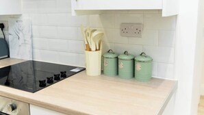 Een keuken met een zwart inductiekookveld, een lichtgekleurd aanrechtblad en drie groene opbergbakken.