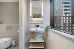 Ein modernes Badezimmer mit Waschbecken, Spiegel und Toilette in Weiß.