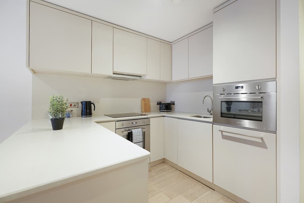 A modern kitchen with white cabinetry, a built-in oven, and a coffee maker.